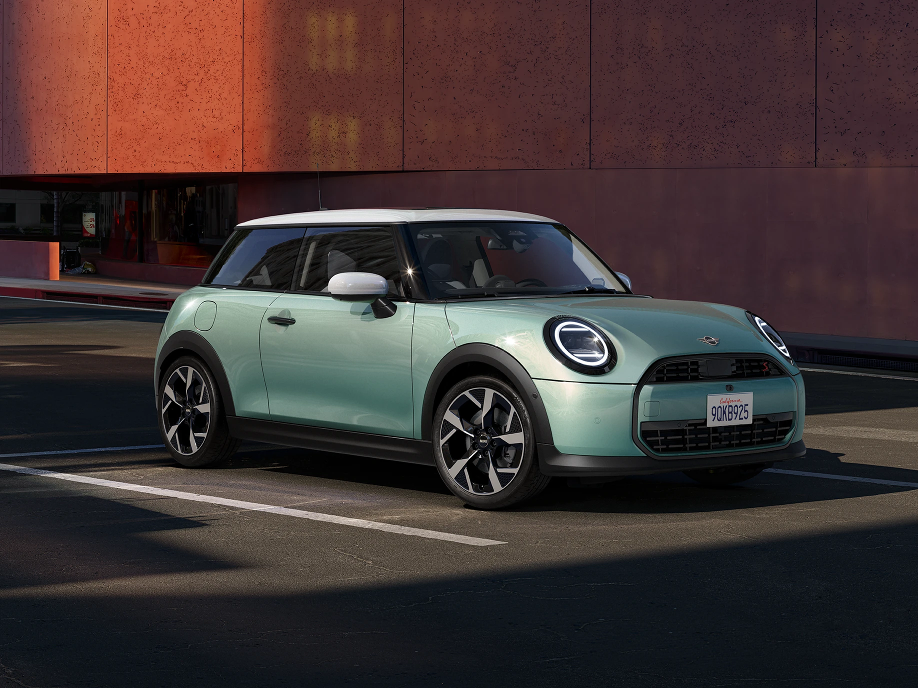 Страничен изглед отпред на MINI Cooper в цвят Ocean Wave Green с бял покрив.