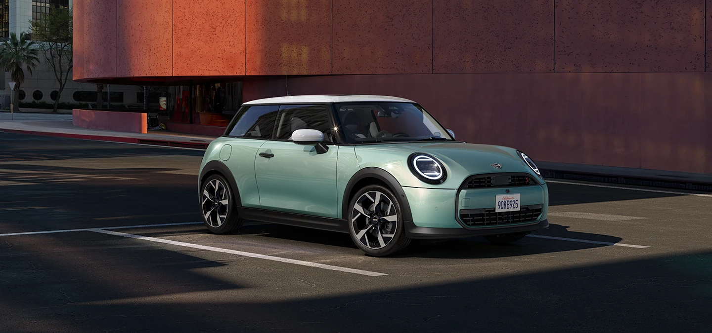 Страничен изглед отпред на MINI Cooper в цвят Ocean Wave Green с бял покрив.