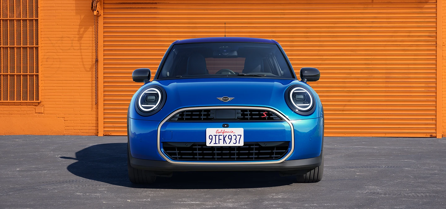 Изглед отпред на MINI Cooper 5 врати в Icy Sunshine Blue и многоцветен покрив в синьо.