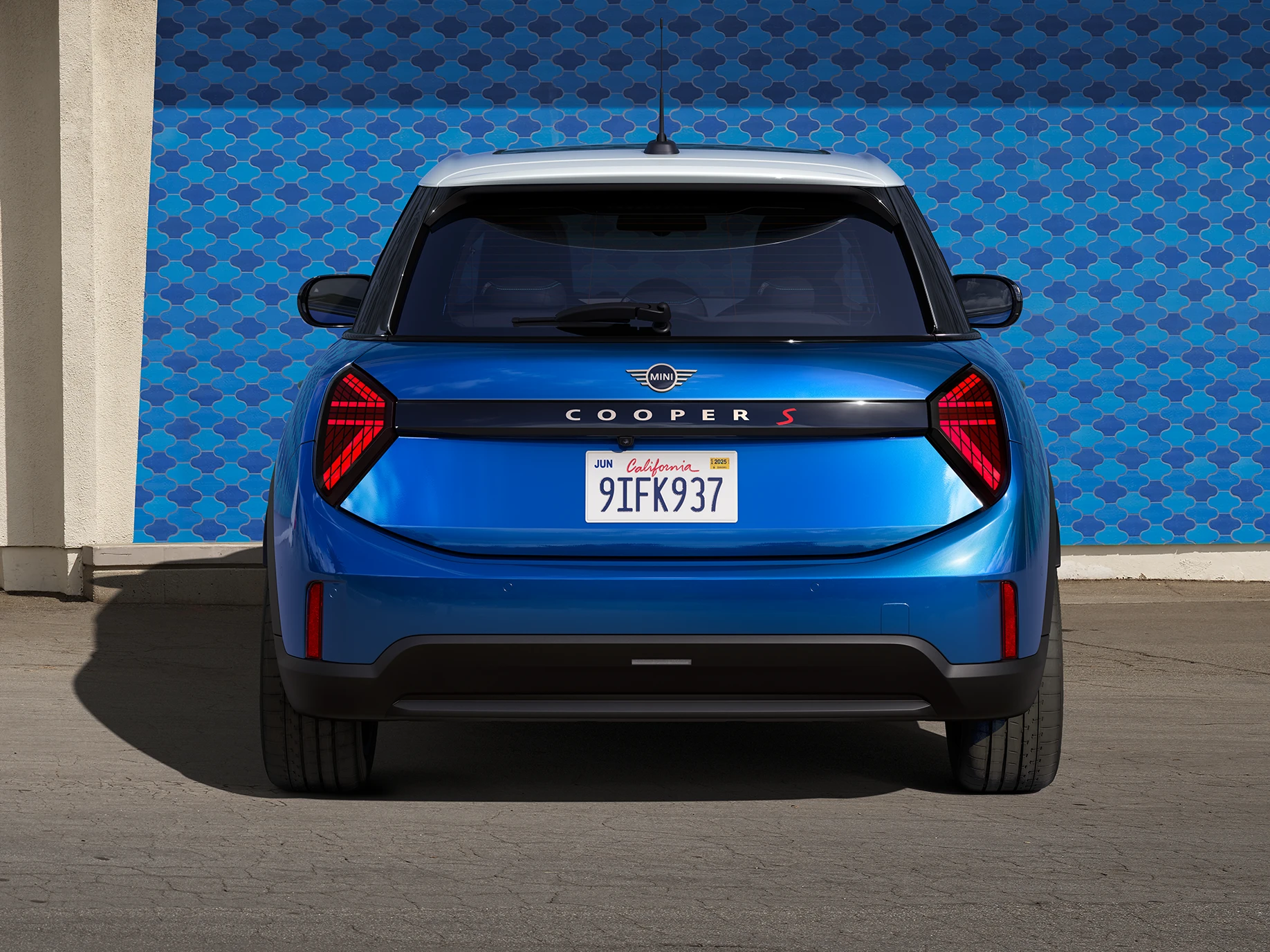 Изглед отзад на MINI Cooper 5 врати в Icy Sunshine Blue и многоцветен покрив в синьо.