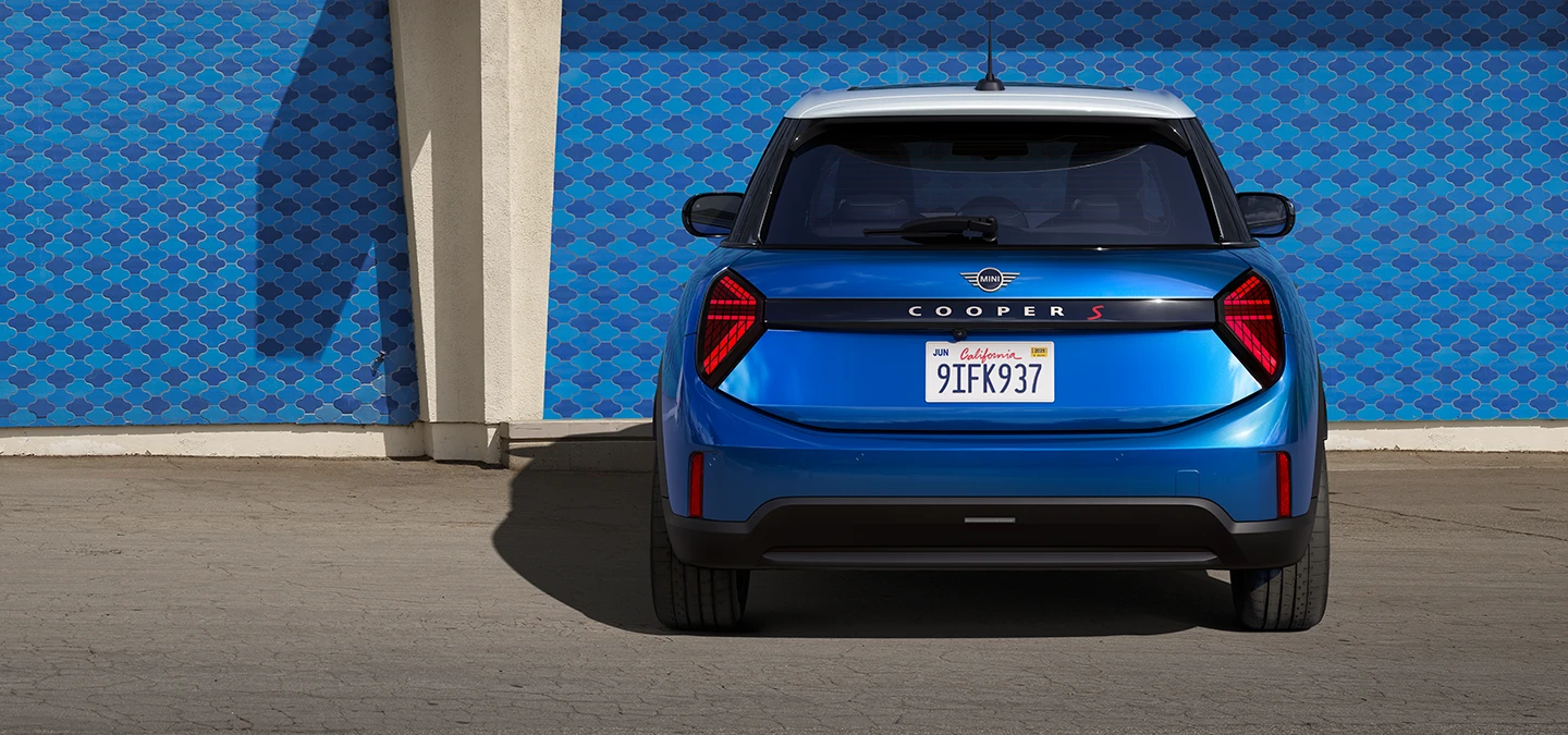 Изглед отзад на MINI Cooper 5 врати в Icy Sunshine Blue и многоцветен покрив в синьо.