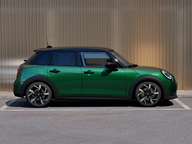 Страничен изглед на паркиращо MINI Cooper 5 врати в British Racing Green и покрив в черно.