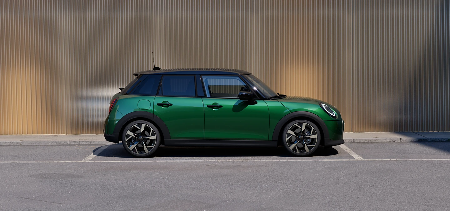 Страничен изглед на паркиращо MINI Cooper 5 врати в British Racing Green и покрив в черно.