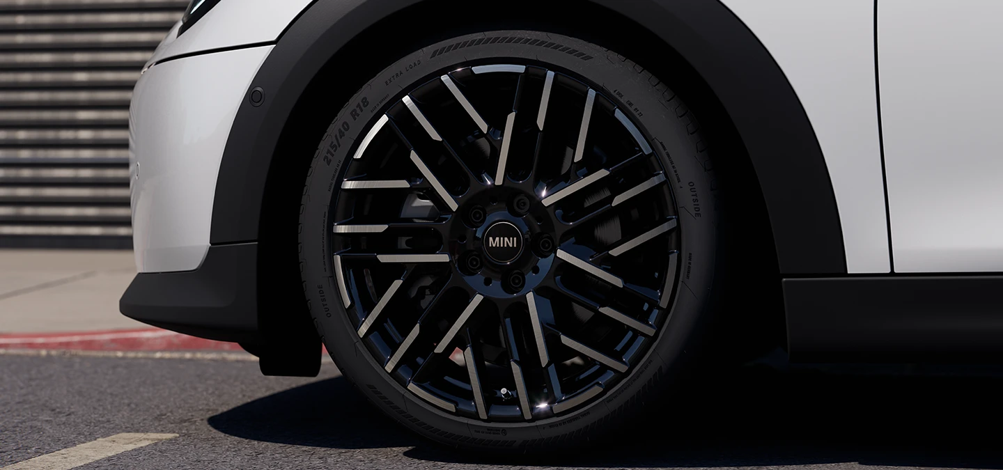 Близък кадър на MINI Cooper 5 врати в Nanuq White с двуцветни джанти Night Flash Spoke.