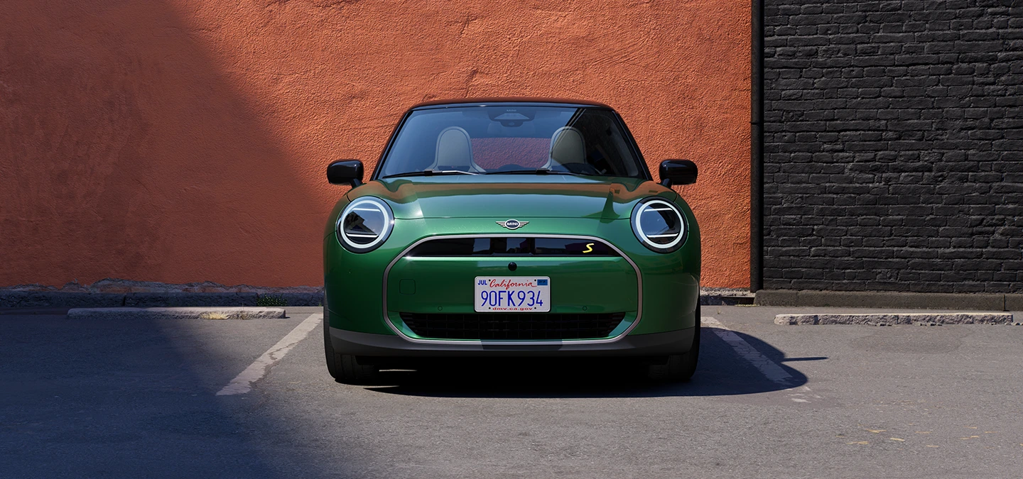 Изглед отпред на изцяло електрическо MINI Cooper в цвят British Racing Green с черен покрив.