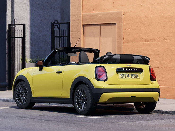 Изглед отзад вляво на паркиращо MINI Cooper Cabrio в цвят Sunnyside Yellow.
