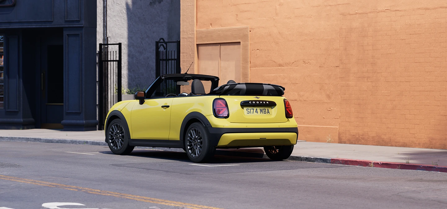 Изглед отзад вляво на паркиращо MINI Cooper Cabrio в цвят Sunnyside Yellow.