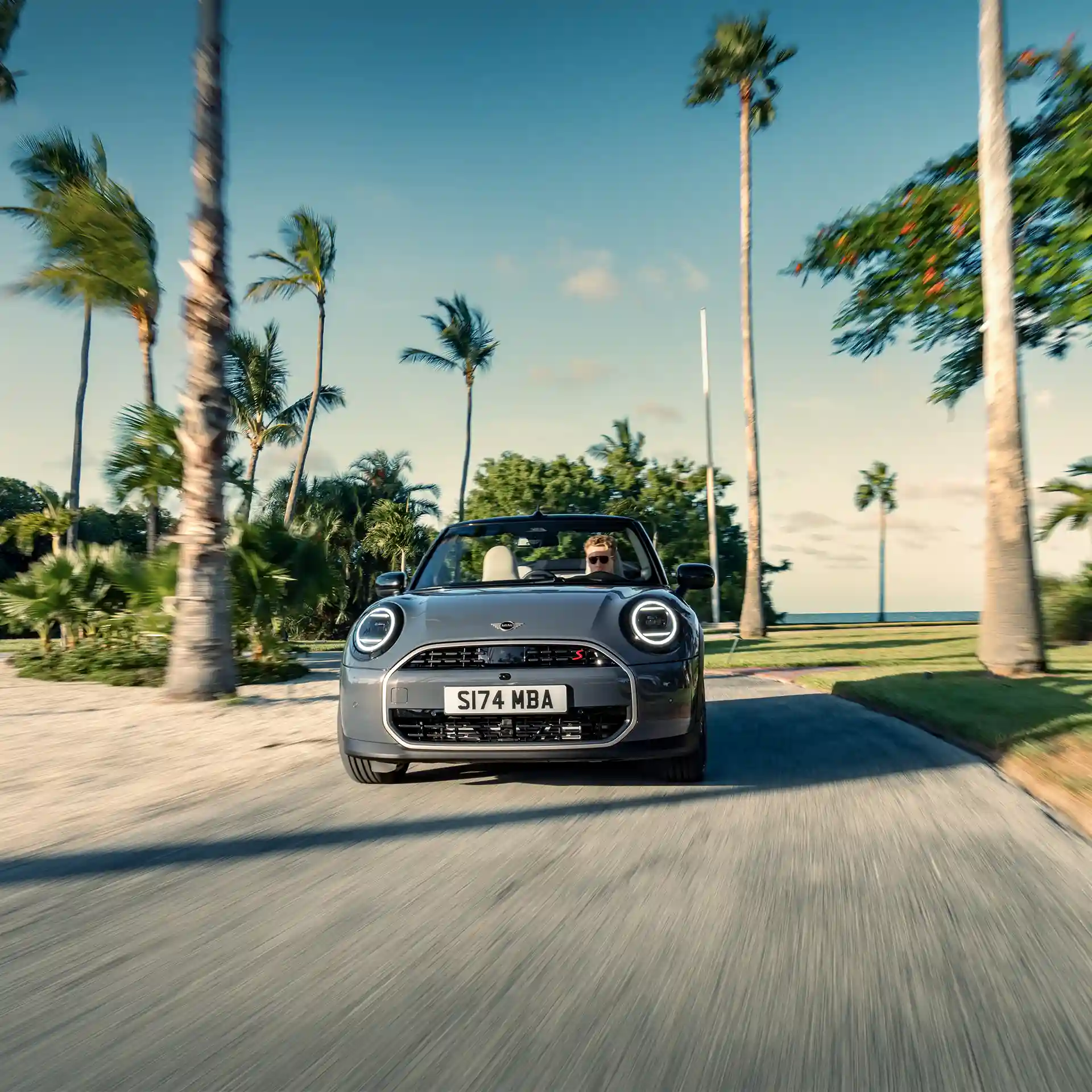 Изглед отпред на движещо се MINI Cooper Cabrio в Copper Grey по улицата