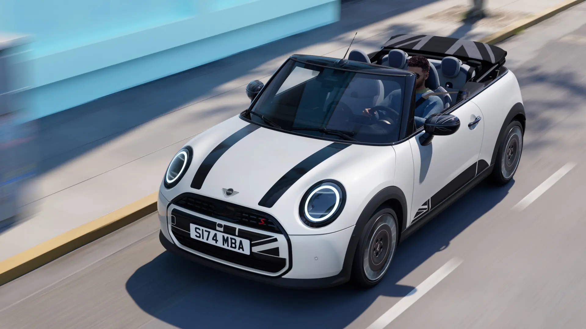 Снимка отгоре на MINI Cabrio в цвят Nanuq White с черни стикери MINI Heritage на предния капак. 