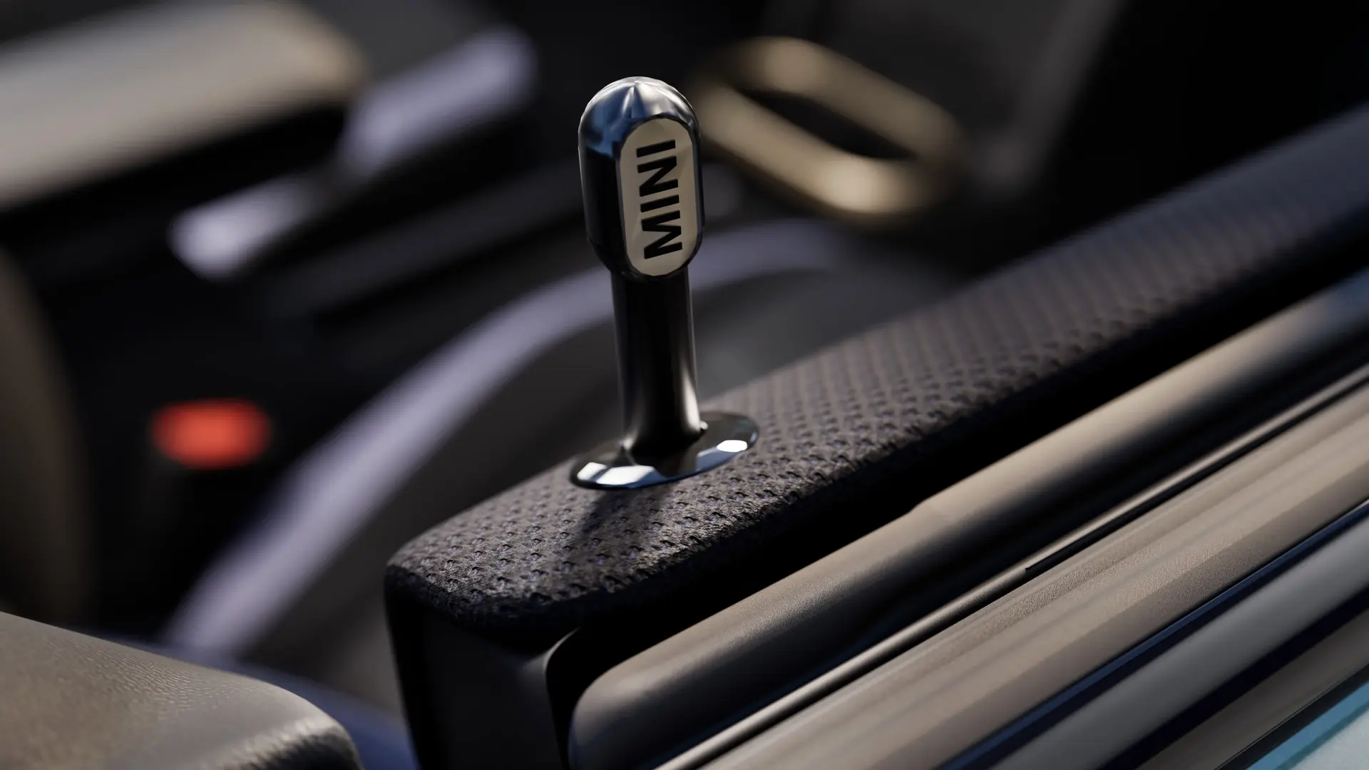 Близък план на оригиналния MINI бутон за заключване на вратата, изработен от черен анодизиран алуминий.