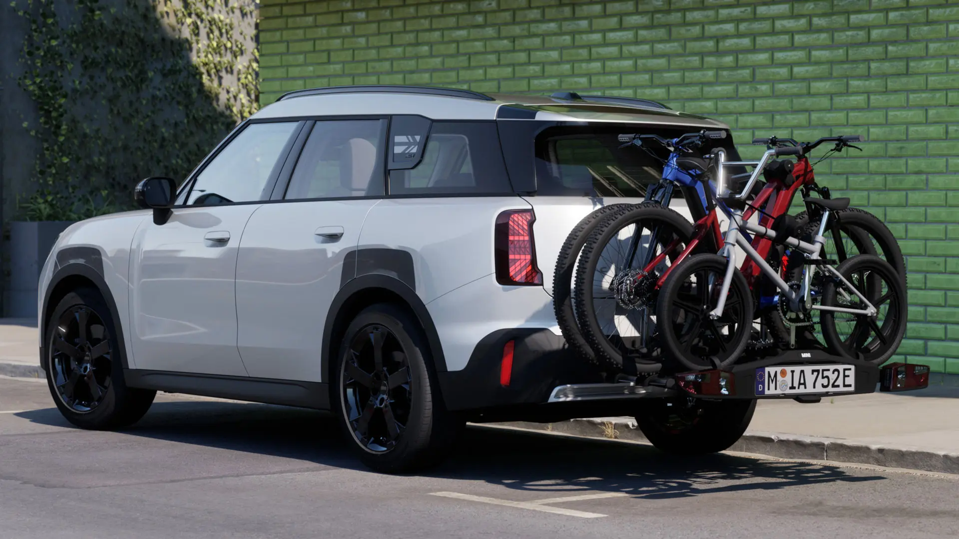 MINI Aceman в цвят Nanuq White, оборудвано с MINI заден багажник за велосипеди Pro 3.0, на който са натоварени два планински велосипеда и един детски велосипед.