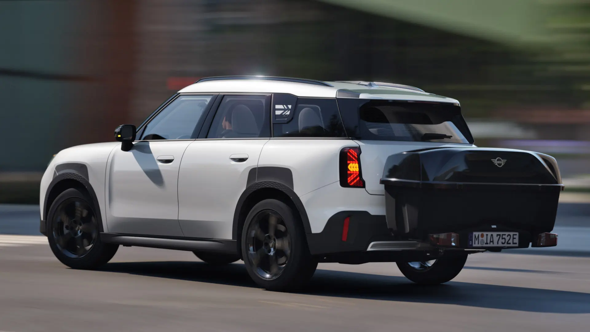 Страничен изглед отзад на MINI Aceman в цвят Nanuq White, оборудвано с MINI заден багажник за велосипеди и MINI задна кутия. 