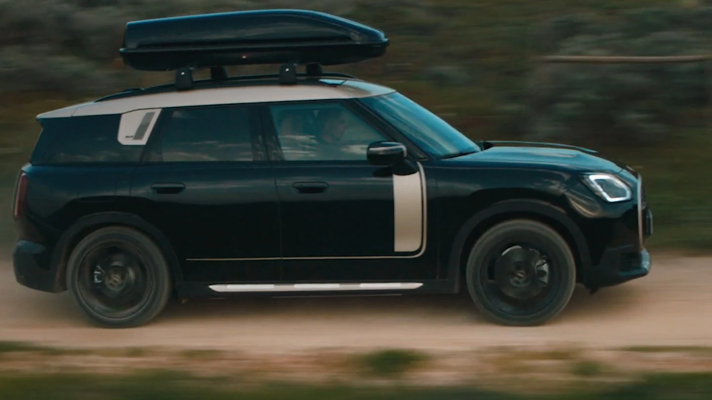 MINI Countryman в цвят Midnight Black metallic с 19-инчови колела John Cooper Works в стил Runway Spoke в черно, шофиращо офроуд. 