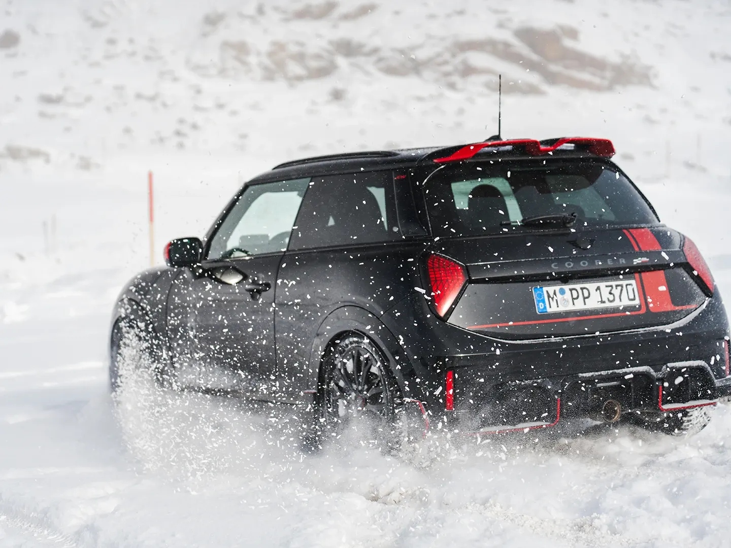 Изглед отзад на MINI Cooper JCW, което се движи в снега.