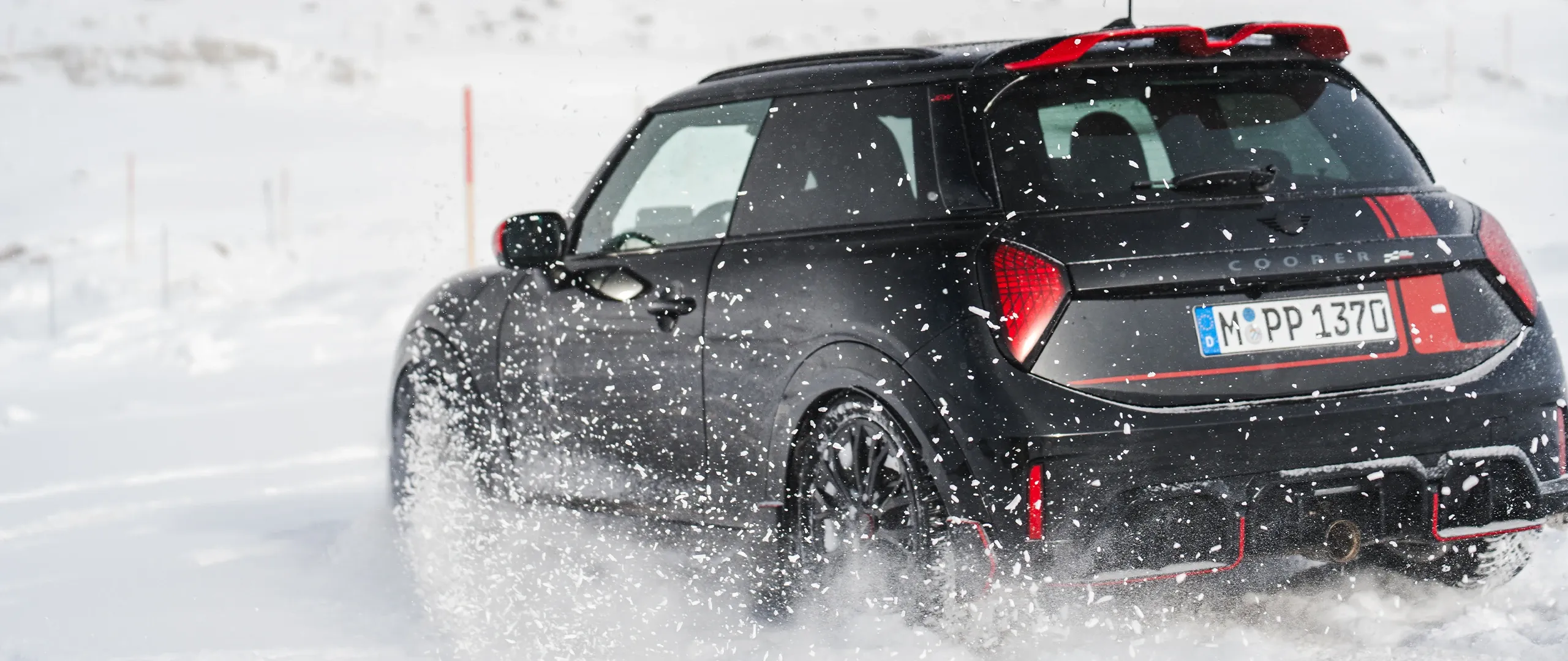 Изглед отзад на MINI Cooper JCW, което се движи в снега.