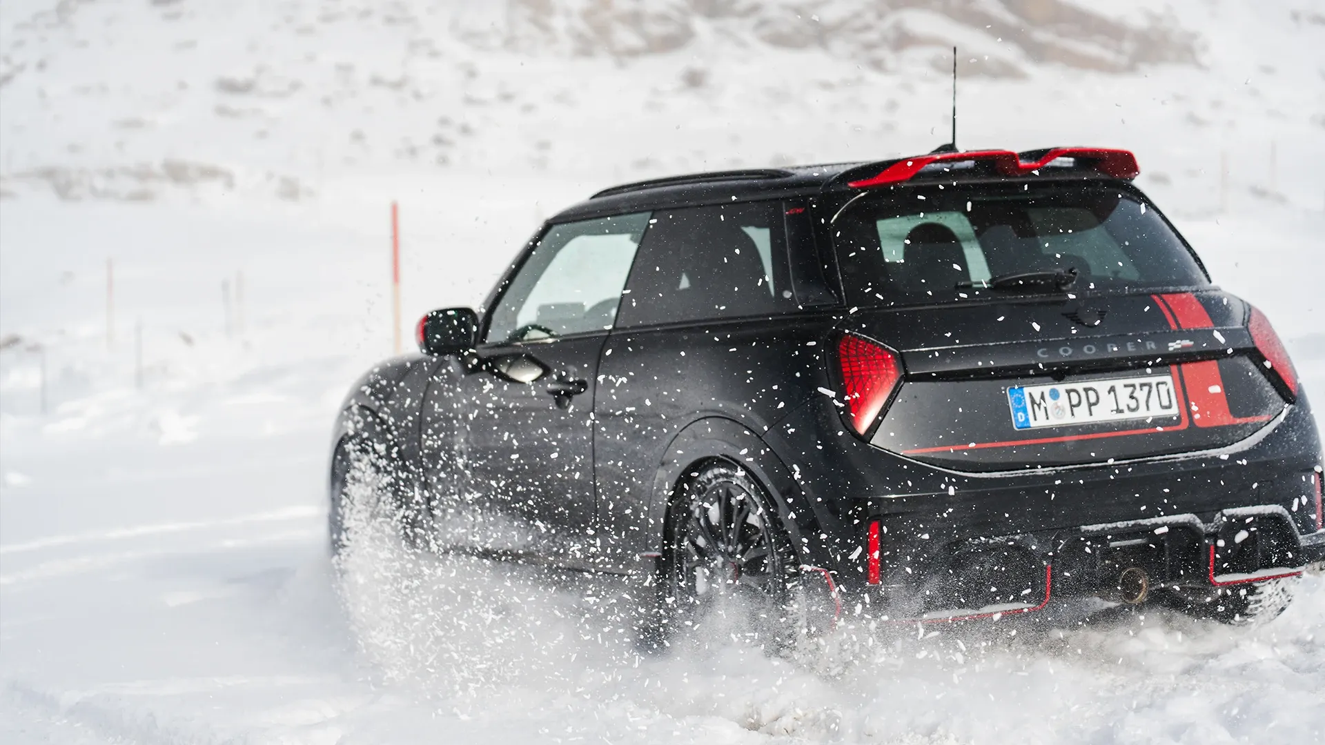 Изглед отзад на MINI Cooper JCW, което се движи в снега.