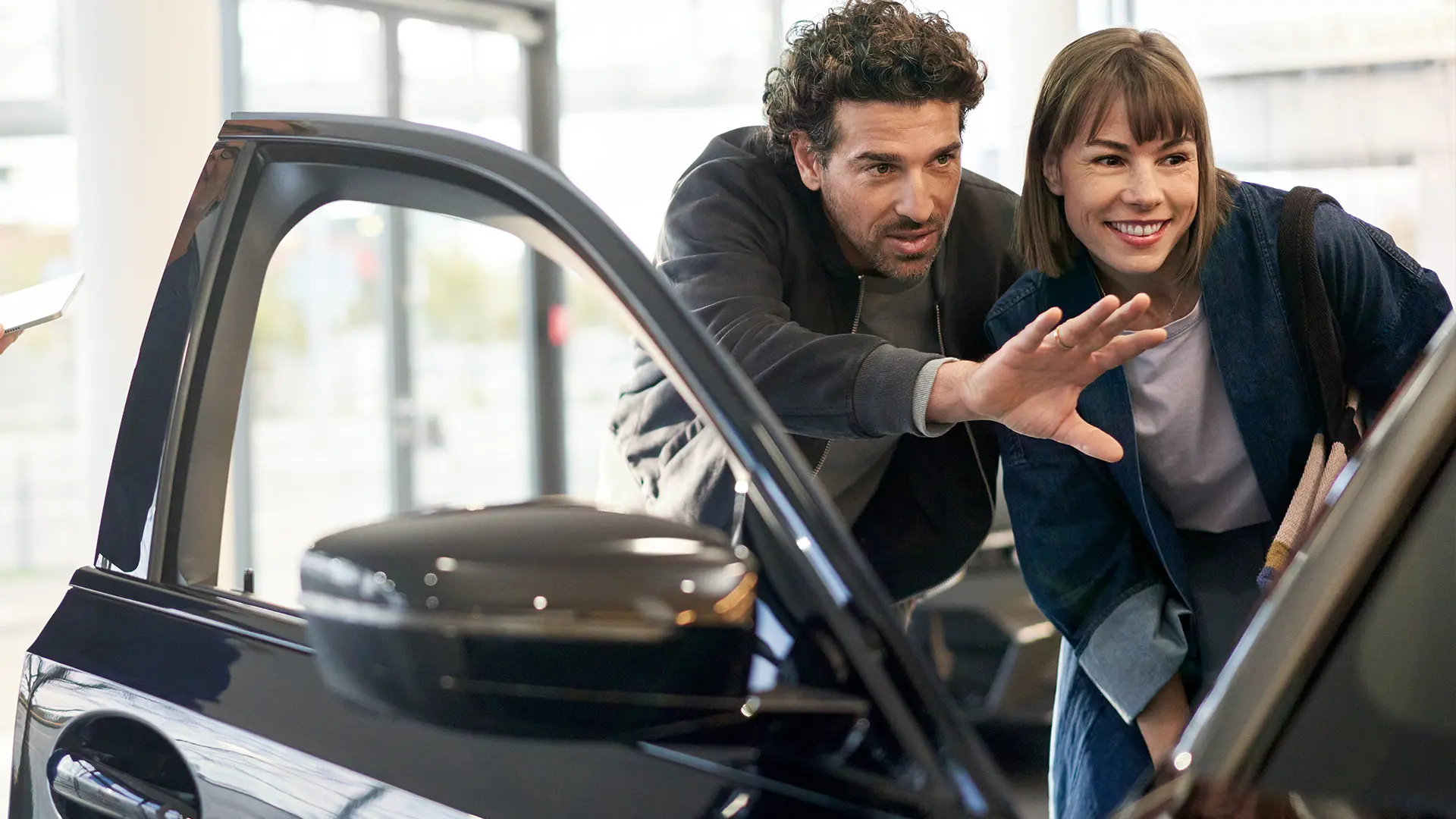 Вътрешността на дилърски център на MINI, където консултант съветва клиент и обяснява характеристиките на интериора.