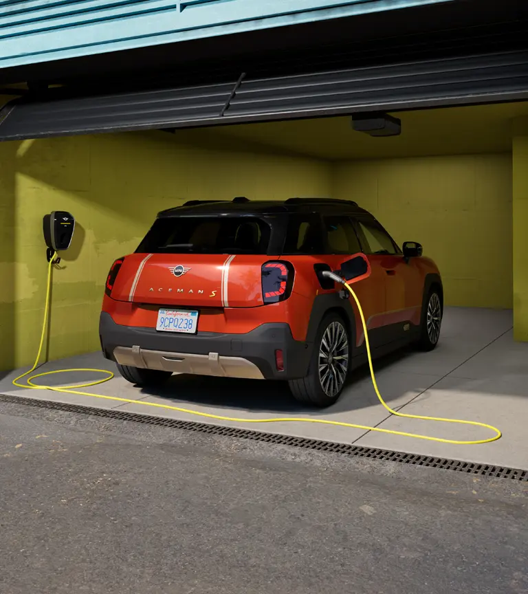 Изцяло електрически MINI Aceman S, който се зарежда с MINI Wallbox Plus, изглед отзад, паркиран в гараж.