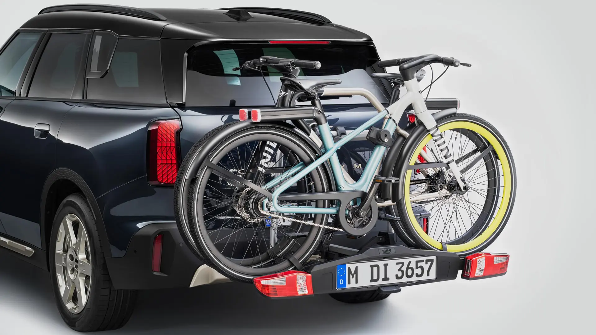 MINI Countryman в черен цвят, оборудван със заден багажник за велосипеди с поставени два планински велосипеда, изглед отзад.